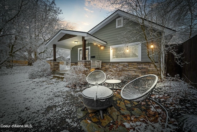 exterior space with a patio area, stone siding, and fence