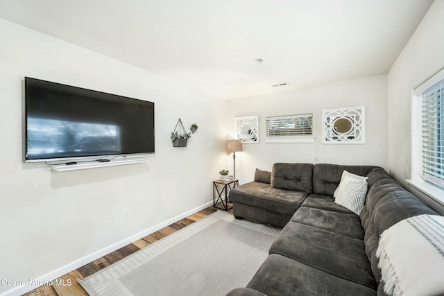 living area featuring visible vents, baseboards, and wood finished floors