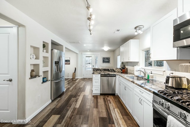 kitchen with light stone countertops, a sink, stainless steel appliances, dark wood-type flooring, and white cabinetry