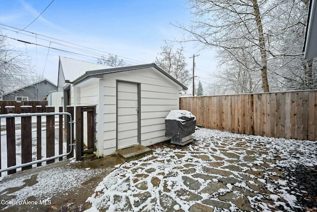 snow covered structure featuring an outbuilding and a fenced backyard