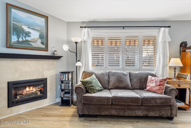 living area with a tile fireplace and wood finished floors