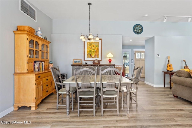 dining area featuring visible vents, baseboards, light wood-type flooring, and an inviting chandelier