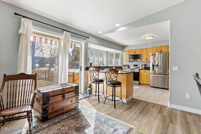 kitchen with dark countertops, a breakfast bar, appliances with stainless steel finishes, a peninsula, and a sink