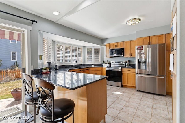 kitchen featuring a peninsula, a kitchen breakfast bar, light tile patterned flooring, stainless steel appliances, and a sink