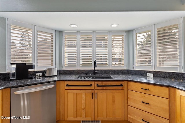 kitchen with stainless steel dishwasher, dark stone counters, recessed lighting, and a sink