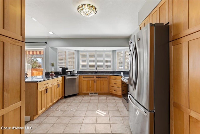 kitchen with dark countertops, visible vents, light tile patterned floors, appliances with stainless steel finishes, and a sink