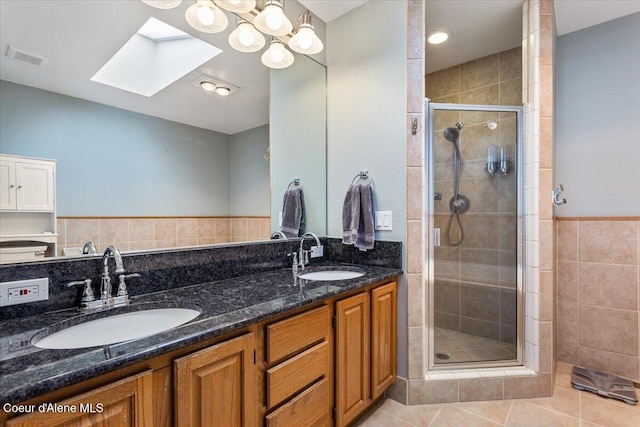 bathroom featuring tile patterned flooring, a shower stall, a skylight, and a sink