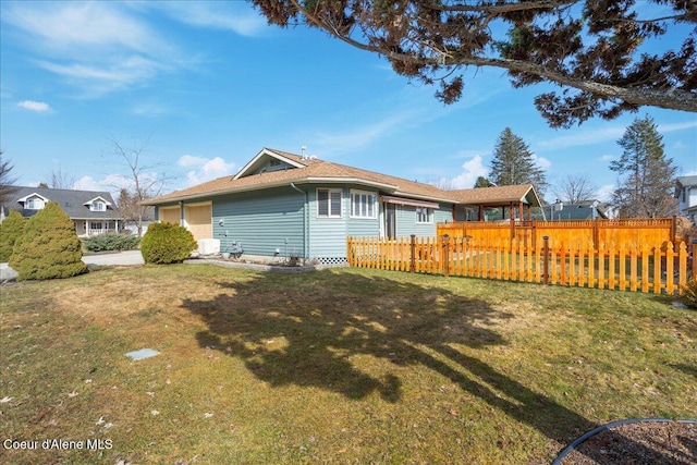 rear view of house with a yard, a garage, and fence