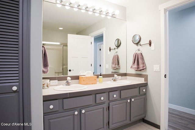 bathroom featuring double vanity, a shower with door, and a sink