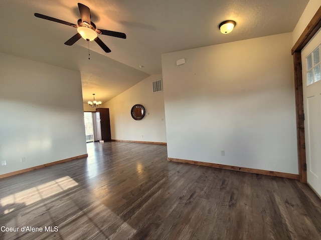 spare room featuring visible vents, ceiling fan with notable chandelier, dark wood-style floors, baseboards, and vaulted ceiling