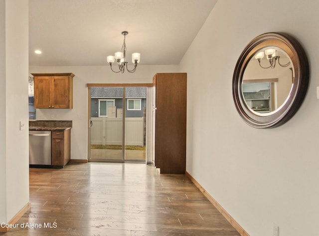 unfurnished dining area featuring a notable chandelier, wood finished floors, and baseboards