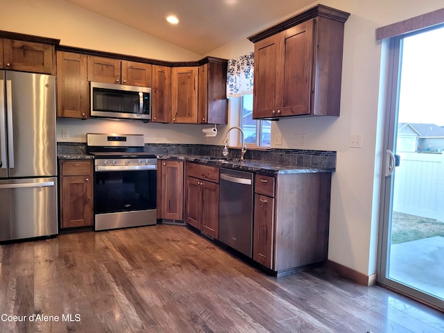 kitchen featuring dark wood finished floors, appliances with stainless steel finishes, lofted ceiling, and a sink