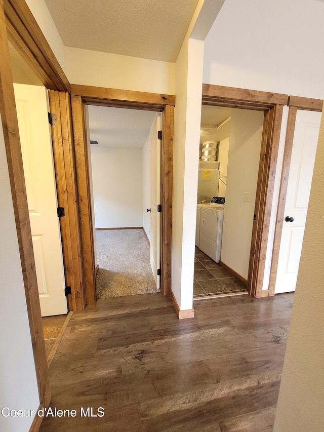 hallway featuring washer and dryer, dark wood-style floors, and baseboards