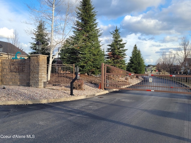 view of street with curbs, a gated entry, and a gate