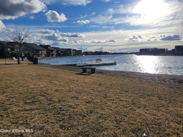 dock area featuring a residential view, a water view, and a lawn