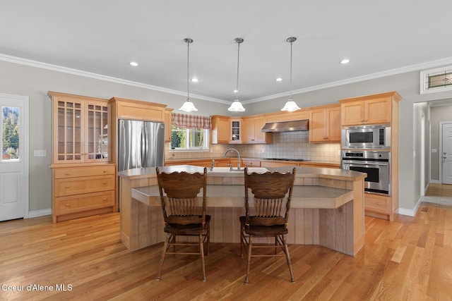 kitchen featuring a center island with sink, light wood-style flooring, light brown cabinetry, range hood, and appliances with stainless steel finishes