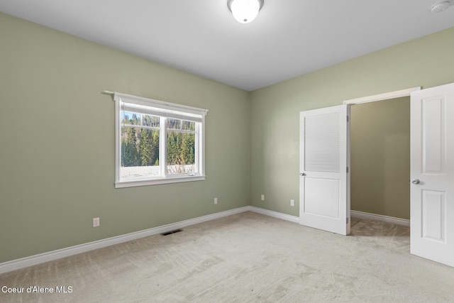 empty room featuring light colored carpet, visible vents, and baseboards