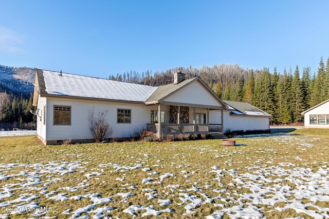 view of front of home featuring crawl space, a wooded view, and a chimney