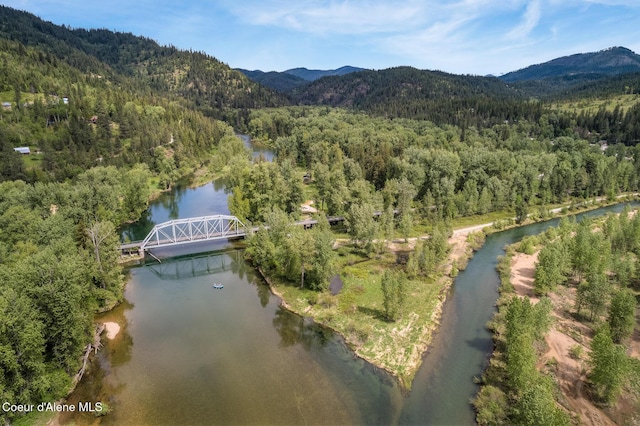 drone / aerial view featuring a wooded view and a water and mountain view