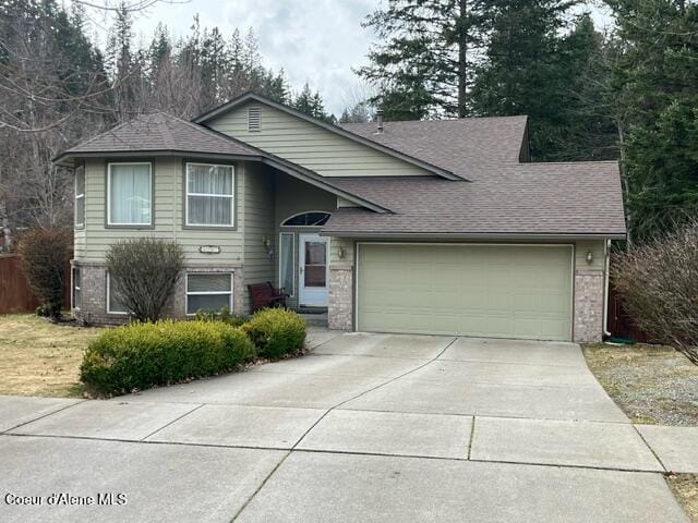 tri-level home with brick siding, driveway, an attached garage, and a shingled roof