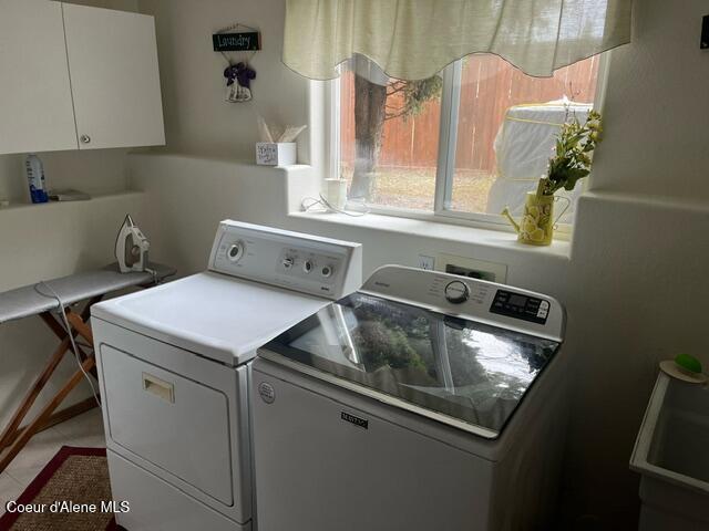 clothes washing area with a sink, cabinet space, and independent washer and dryer