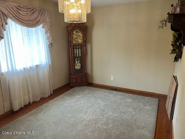 empty room with a chandelier, visible vents, heating unit, and baseboards