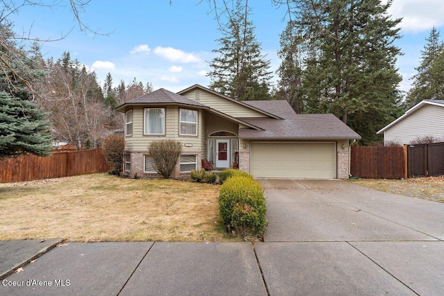 view of front of property featuring a front yard, concrete driveway, fence, and an attached garage