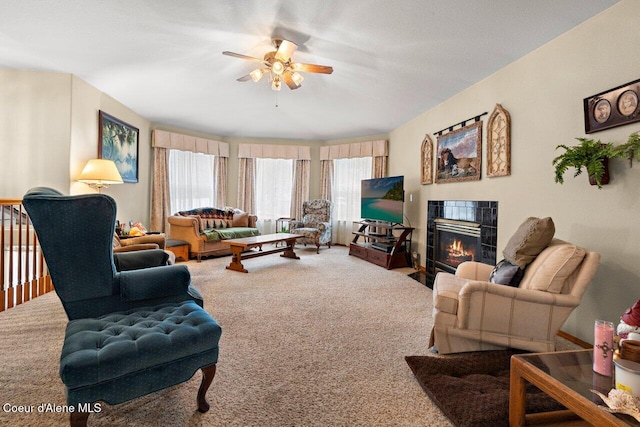 living area featuring a tiled fireplace, carpet, and ceiling fan