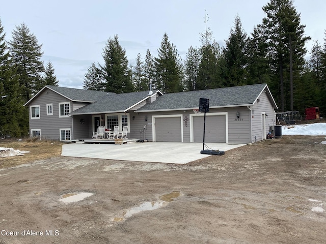 view of front facade featuring central air condition unit, concrete driveway, a garage, and a shingled roof