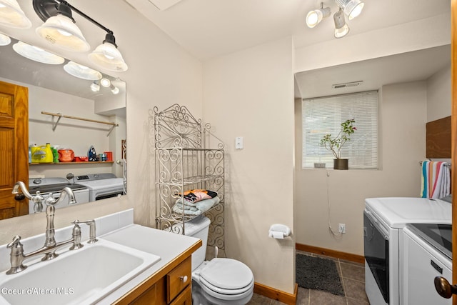 bathroom featuring tile patterned flooring, toilet, vanity, baseboards, and separate washer and dryer