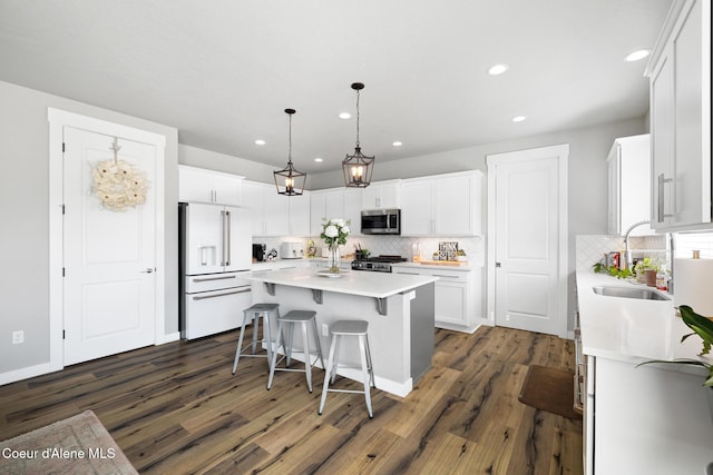 kitchen featuring a sink, stainless steel microwave, a center island, high end white fridge, and white cabinets