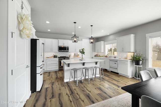 kitchen featuring a kitchen island, a kitchen bar, premium appliances, white cabinetry, and a sink