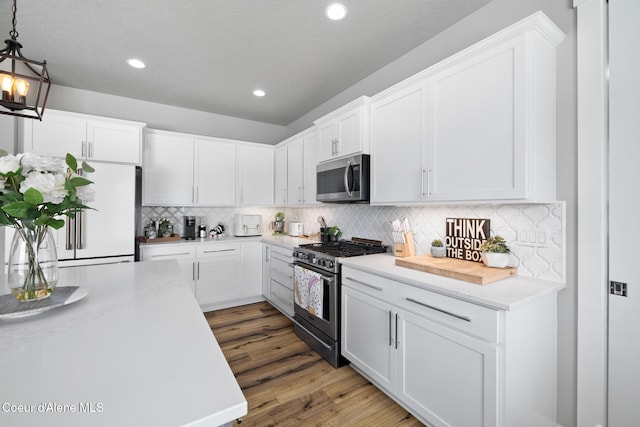 kitchen featuring tasteful backsplash, wood finished floors, white cabinetry, recessed lighting, and appliances with stainless steel finishes