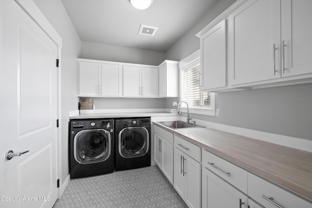 washroom featuring cabinet space, visible vents, independent washer and dryer, and a sink
