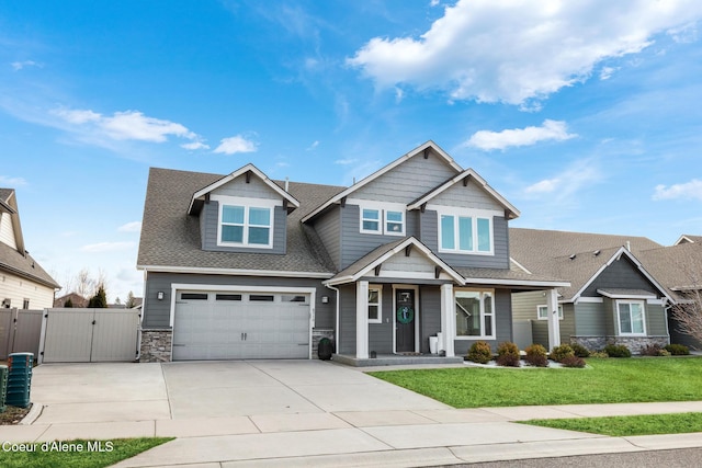 craftsman-style home featuring a gate, driveway, a shingled roof, a front lawn, and stone siding