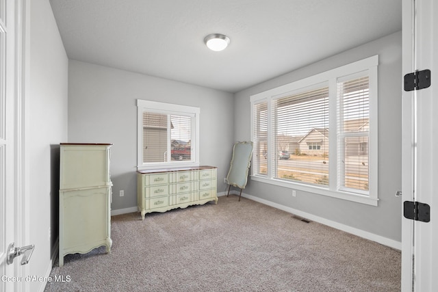 carpeted bedroom featuring multiple windows, baseboards, and visible vents