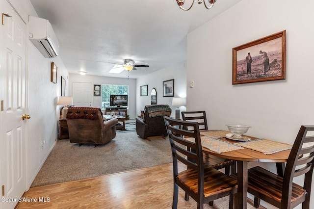 dining space featuring light carpet, an AC wall unit, a ceiling fan, light wood finished floors, and baseboards