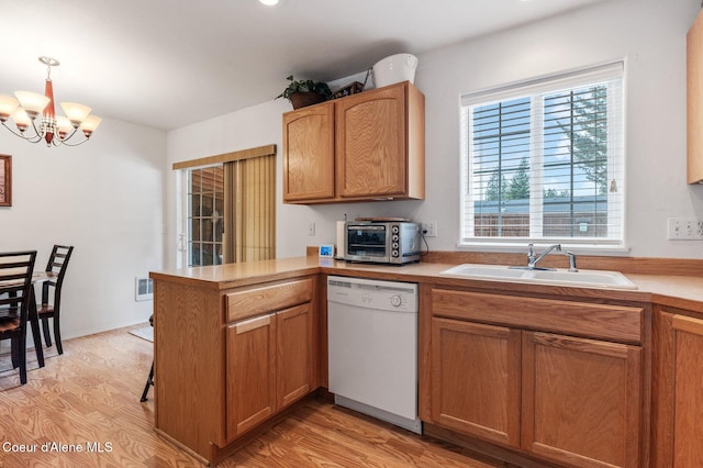 kitchen featuring a sink, light wood-style floors, a peninsula, a toaster, and dishwasher