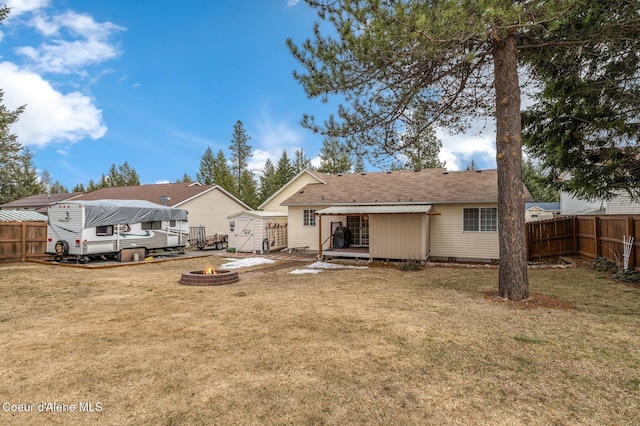 rear view of property featuring crawl space, a fire pit, a yard, and fence