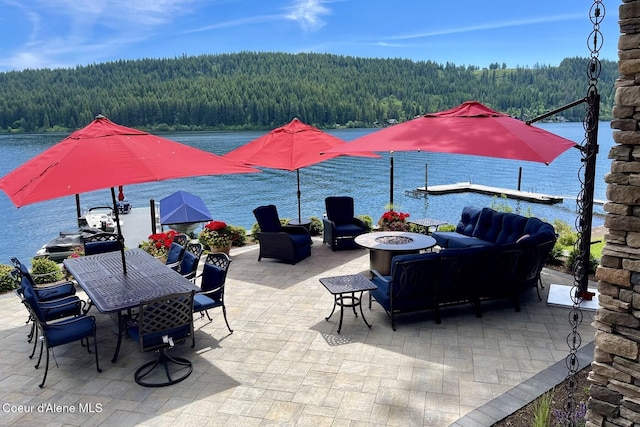 view of patio / terrace with a forest view, a water view, a fire pit, and outdoor dining space