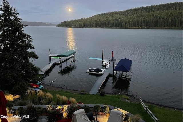 dock area featuring boat lift, a forest view, and a water view