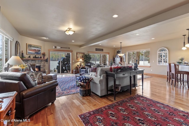 living area with recessed lighting, a fireplace, baseboards, and light wood finished floors