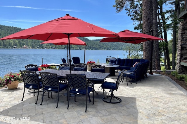 view of patio with outdoor dining space, a wooded view, a water view, and an outdoor fire pit