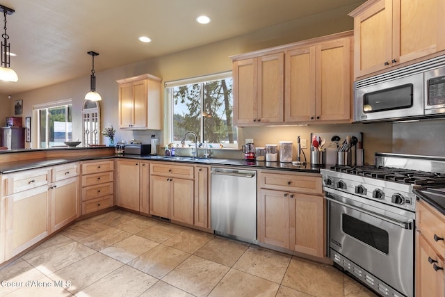 kitchen featuring dark countertops, appliances with stainless steel finishes, a peninsula, and light brown cabinets