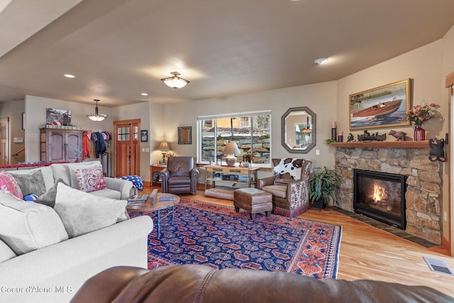 living room with recessed lighting, visible vents, a stone fireplace, and wood finished floors