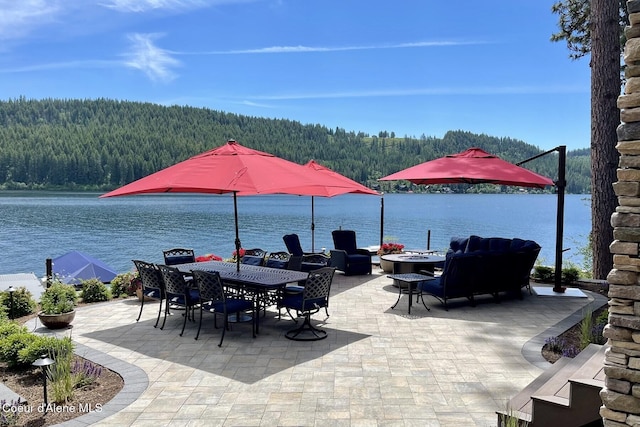 view of patio / terrace featuring outdoor dining area, a view of trees, a water view, and a fire pit