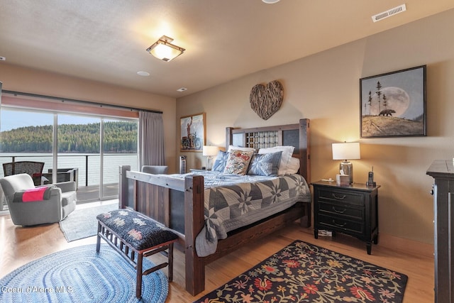 bedroom featuring access to exterior, wood finished floors, visible vents, and baseboards