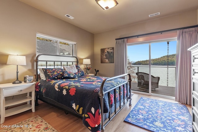 bedroom with visible vents, wood finished floors, and access to outside