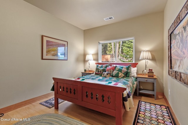 bedroom featuring visible vents, baseboards, and wood finished floors