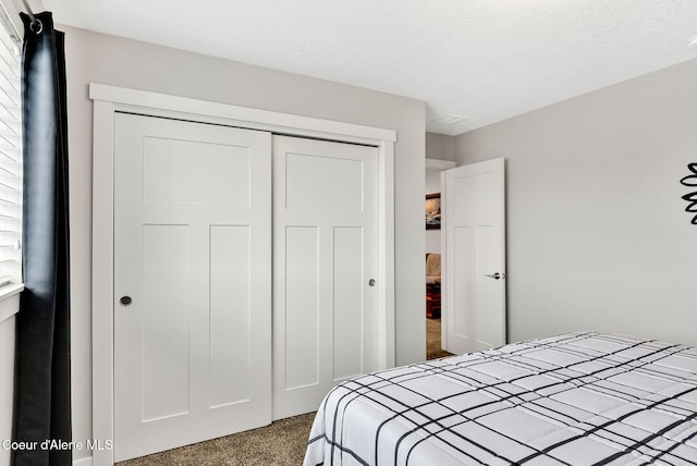 bedroom featuring a closet, a textured ceiling, and dark carpet